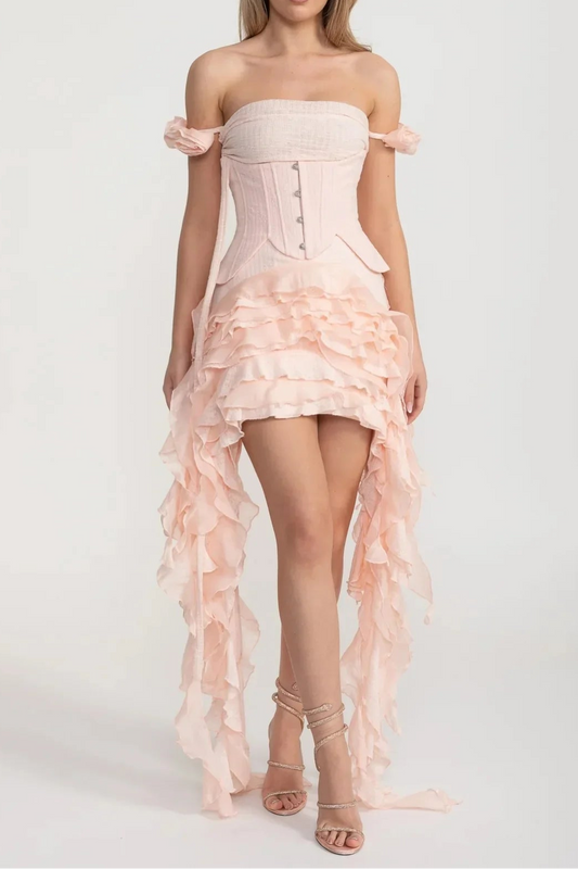 Woman wearing a light pink strapless dress with ruffled layers on a white background