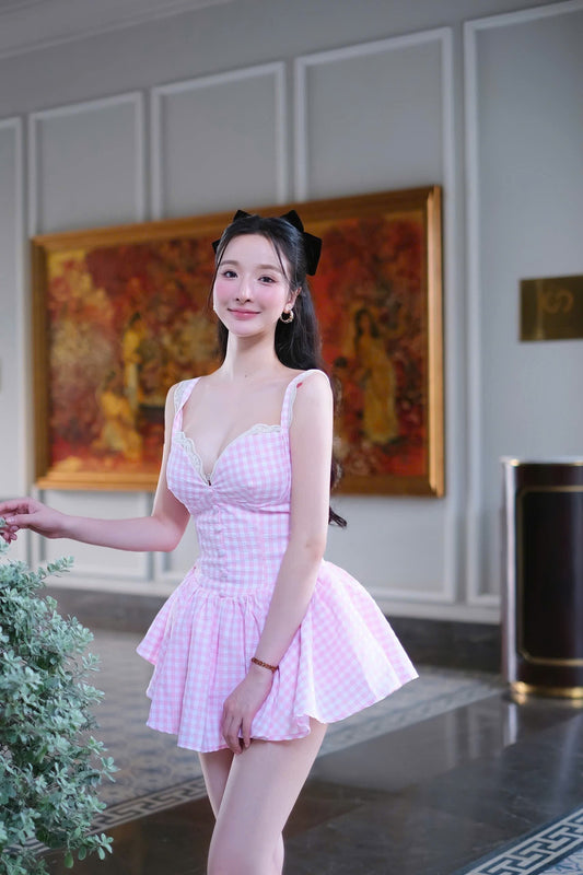 Woman in a pink dress standing in an elegant interior setting with a painting in the background.
