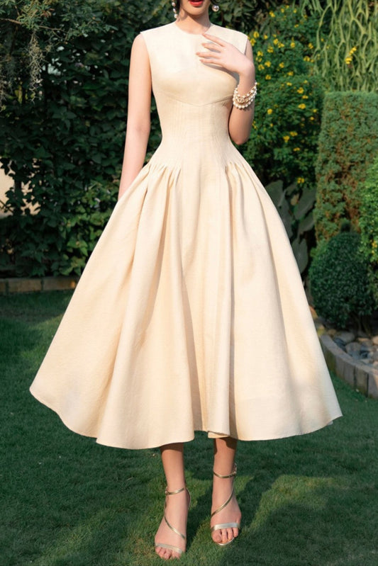 A woman wearing a beige sleeveless corset midi dress with a sweetheart neckline, standing outdoors.