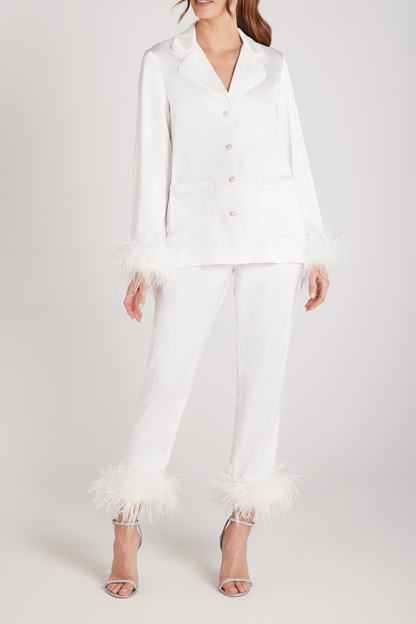 Woman wearing a white outfit with ruffled pants on a white background