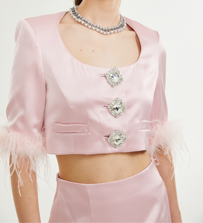 Woman wearing a pink outfit with feather details and embellishments on a white background