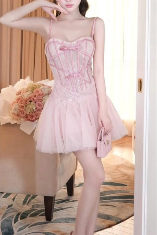 Woman wearing a pink dress with floral decorations in an indoor setting.