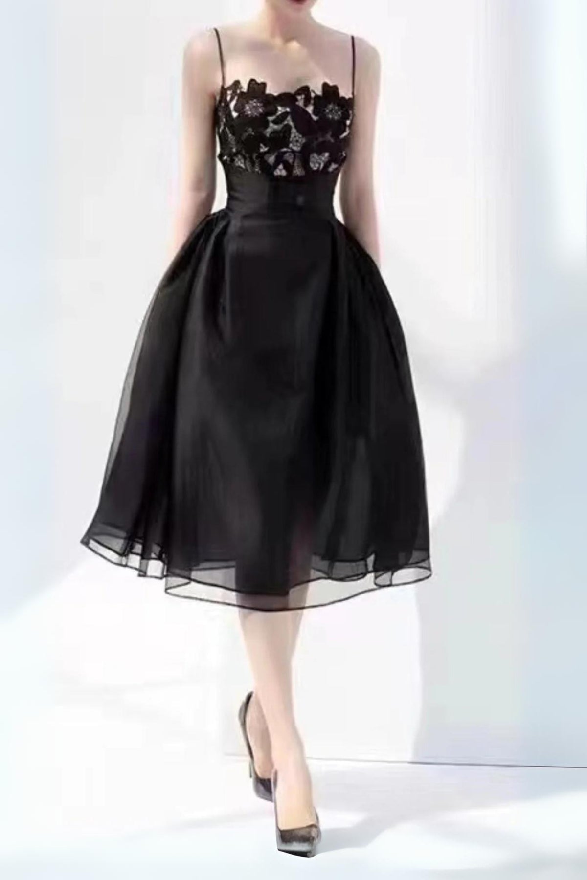 A midi black lace camisole dress with a flared skirt, high waist, gathered sides, and a floral lace pattern. The dress features a camisole-style neckline and a back zipper.