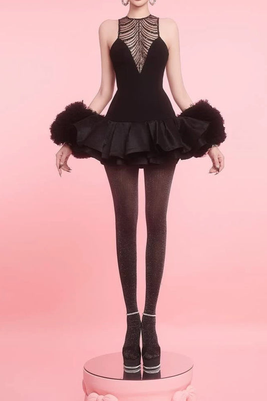 Model wearing a black dance costume with feathered sleeves on a pink background