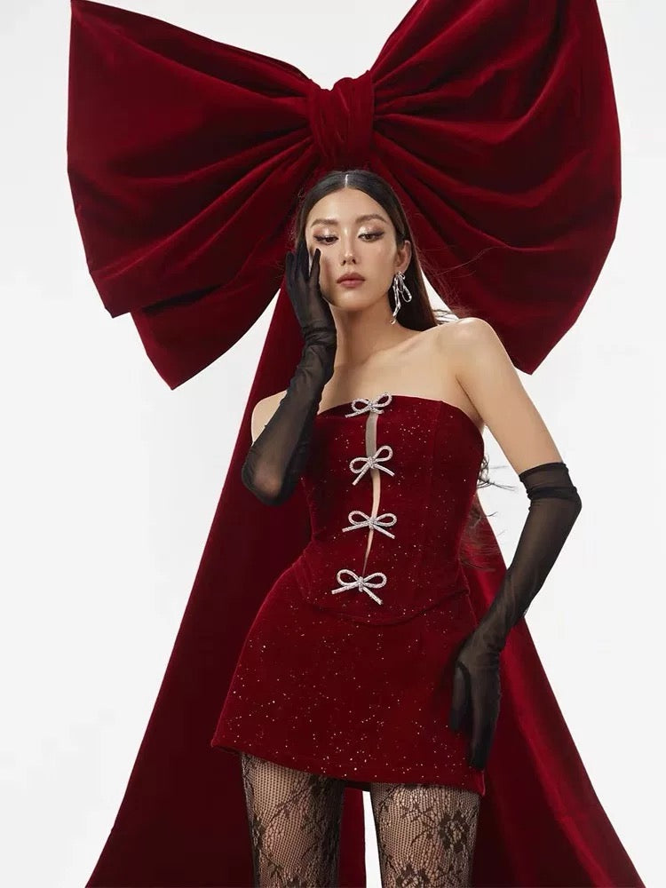 Woman in a red dress with a large red bow in the background