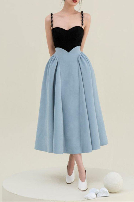 Woman wearing a black top and light blue skirt on a beige background