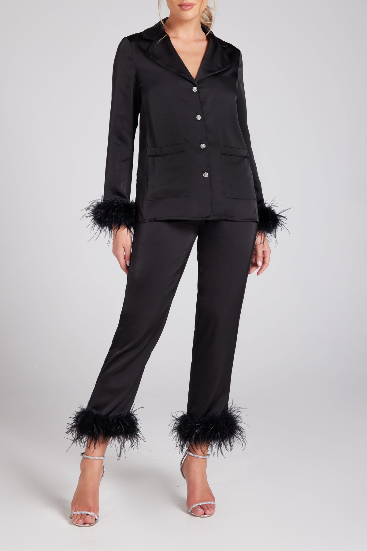 Woman wearing a black outfit with feathered cuffs on a white background