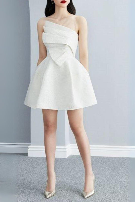 A woman wearing a white mini dress with a strappy hem design, standing against a neutral background.