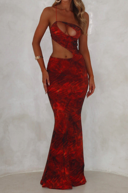 A model wearing an orange maxi dress with a mesh fabrication, featuring an asymmetrical backline and an exclusive print.
