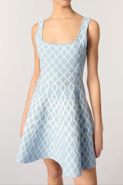 Woman wearing a light blue patterned dress on a plain background