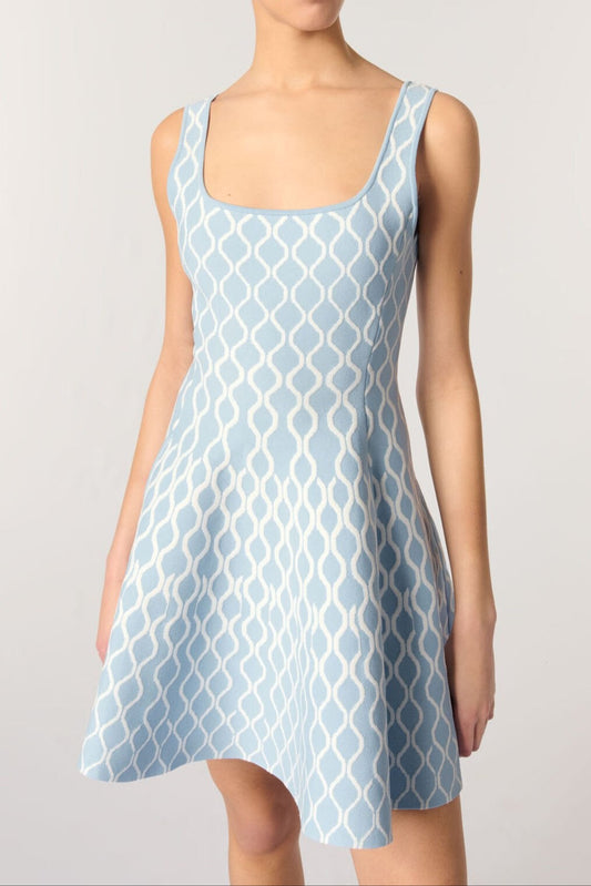 Woman wearing a light blue patterned dress on a plain background