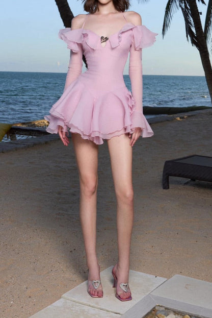 Woman in a pink dress standing on a beach with palm trees and ocean in the background